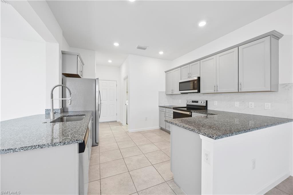 4583 Lamaida Lane Immokalee, FL 34142 - Photo 9 of 29 a kitchen with stainless steel appliances granite countertop a sink refrigerator and microwave