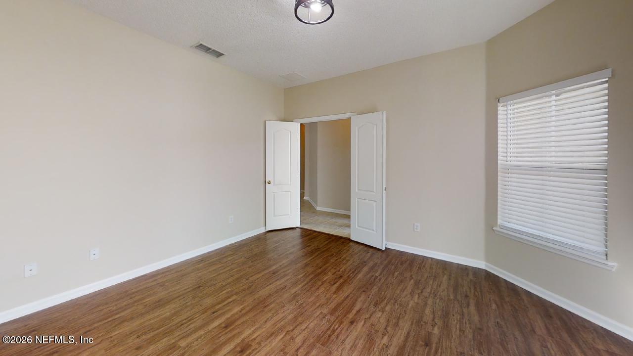 14454 Millhopper Road Jacksonville, FL 32258 - Photo 36 of 44 a view of an empty room with wooden floor and a window