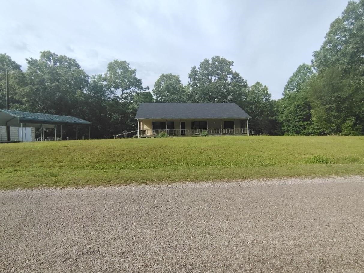 Single-story residence set on an expansive green lawn, featuring a covered porch with white columns