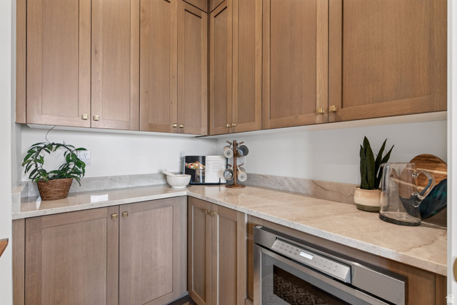12308 Mariah Circle Draper, UT 84020 - Photo 190 of 293 Guest House Kitchenette or pantry area featuring light wood-finish cabinetry with brass hardware, light-toned stone countertops, and a built-in stainless steel microwave