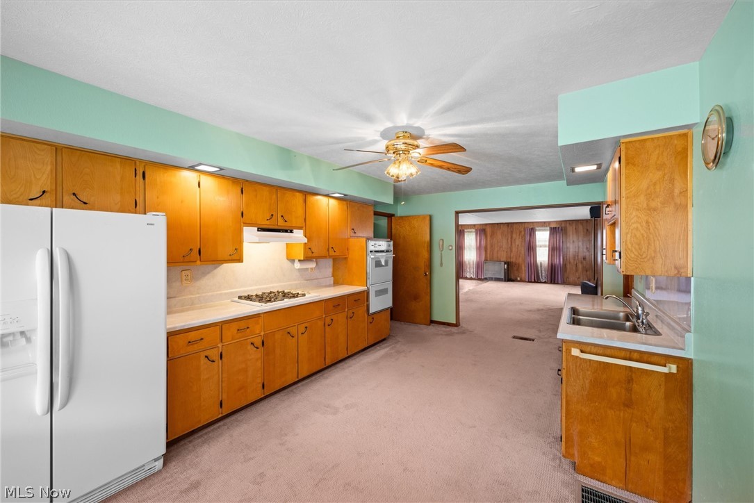 316 Deerwood Road Huron, OH 44839 - Photo 6 of 37 Kitchen featuring ceiling fan, tasteful backsplash, light carpet, sink, and white appliances