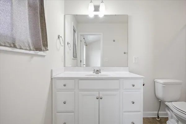 a bathroom with a granite countertop sink a toilet and a mirror
