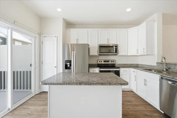 a kitchen with granite countertop a refrigerator a stove a sink a microwave and cabinets
