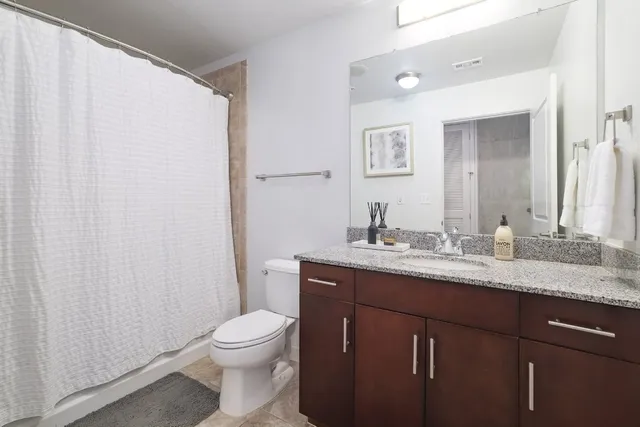 a bathroom with a granite countertop bathtub shower and toilet