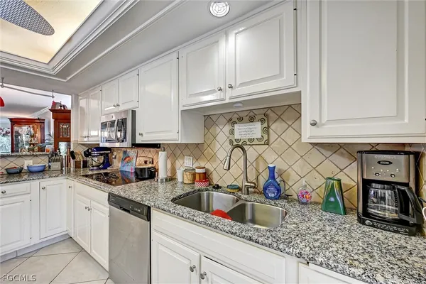 a kitchen with stainless steel appliances granite countertop a sink a stove and a white cabinets