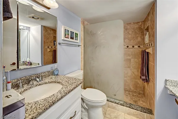 a bathroom with a granite countertop sink toilet and shower
