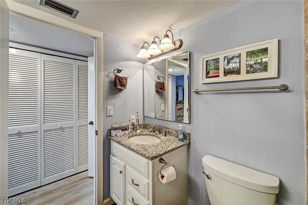 a bathroom with a granite countertop sink vanity mirror and toilet