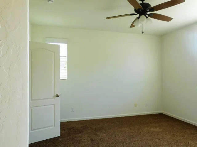 an empty room with a ceiling fan and a window