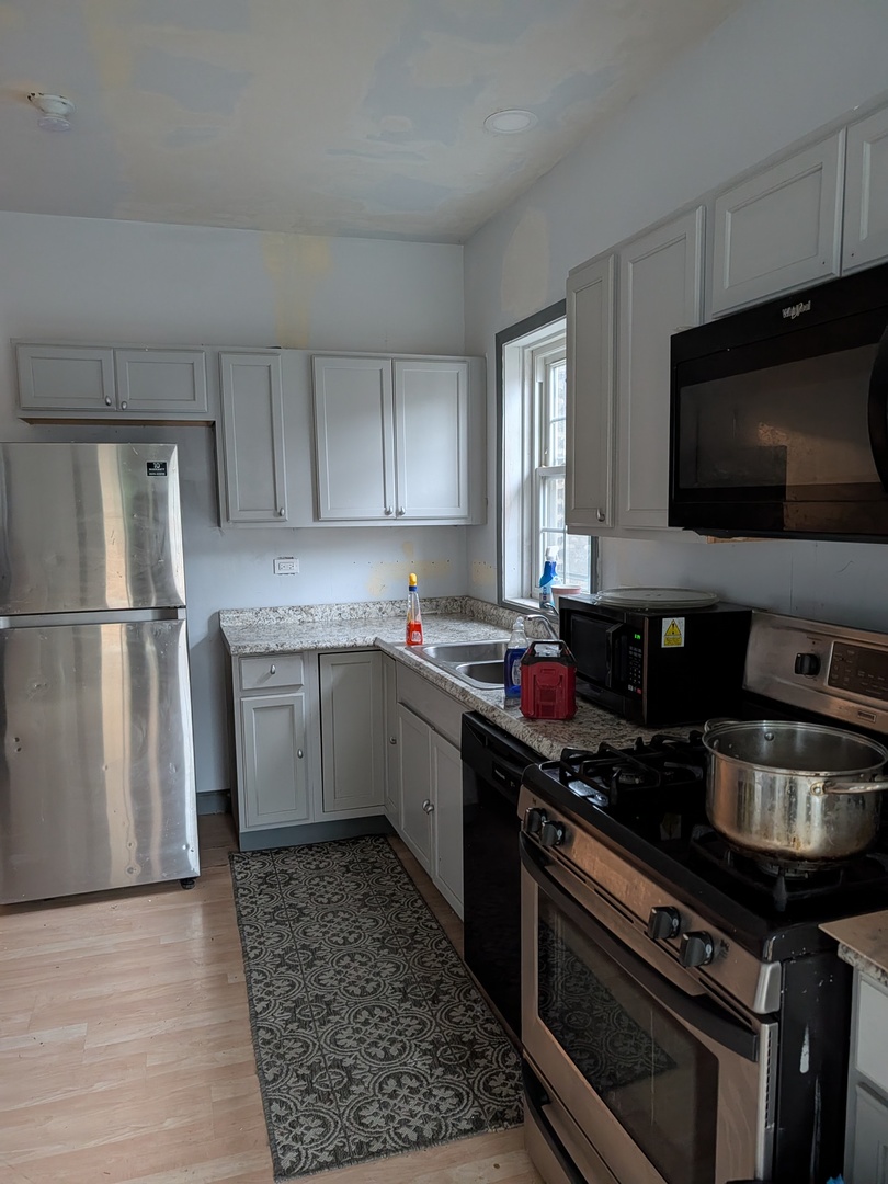 5041 West George Street Chicago, IL 60641 - Photo 6 of 11 a kitchen with a sink appliances and cabinets