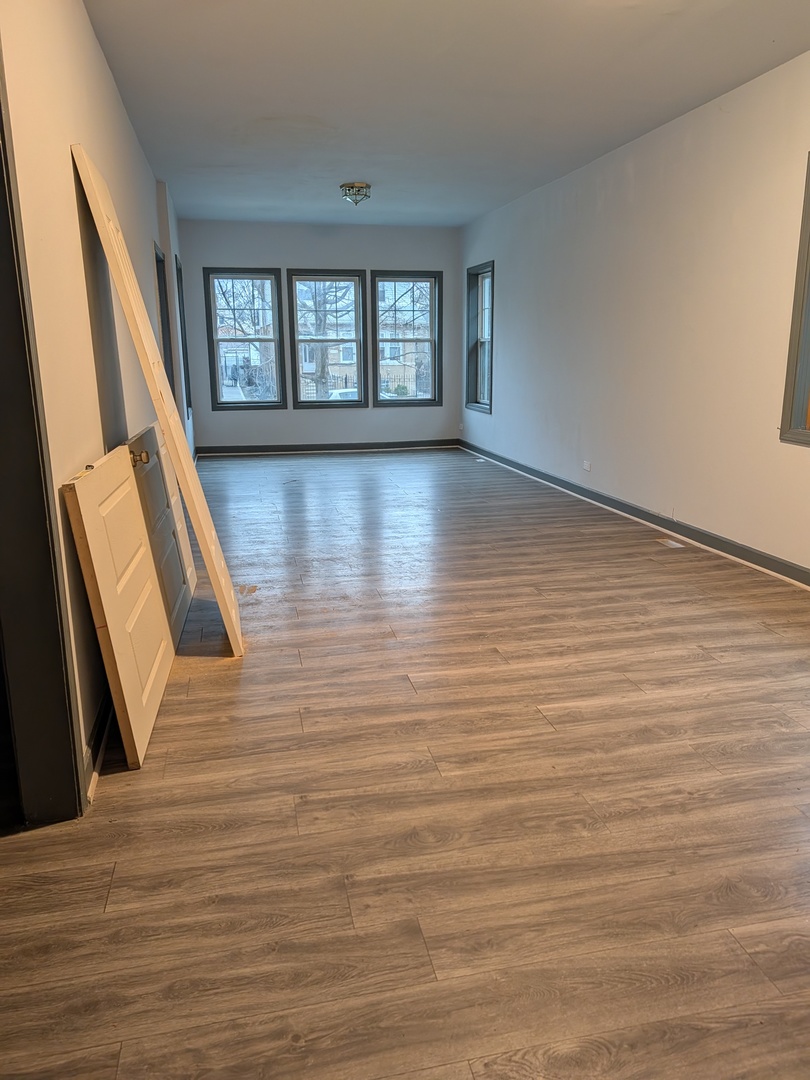 5041 West George Street Chicago, IL 60641 - Photo 7 of 11 a view of an empty room with wooden floor and a window