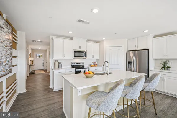 an open kitchen with stainless steel appliances a refrigerator a stove top oven and a center island