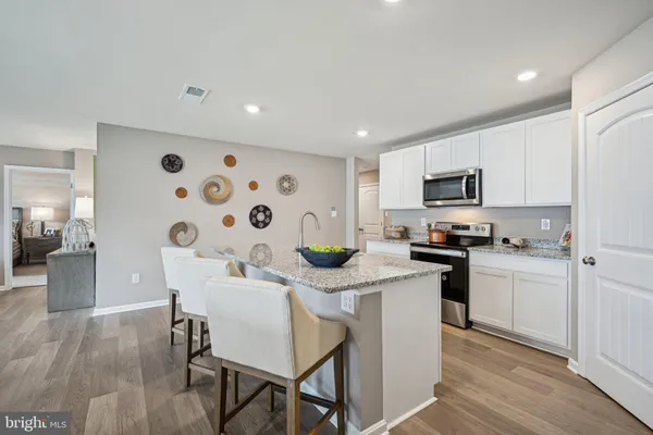 a kitchen with stainless steel appliances kitchen island granite countertop a sink a stove a refrigerator cabinets and dining table