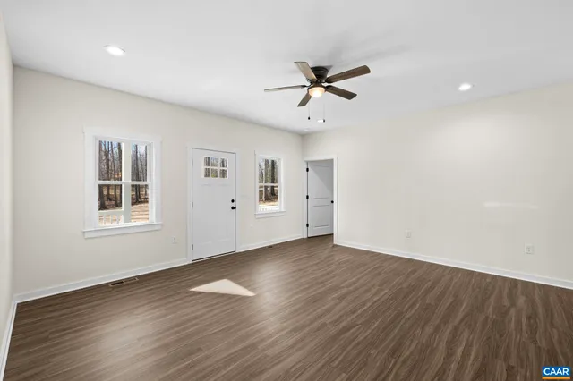 an empty room with wooden floor ceiling fan and window