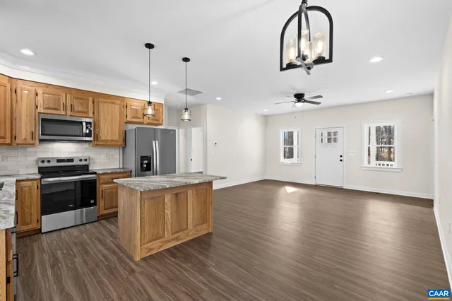 a kitchen with stainless steel appliances granite countertop a refrigerator a stove top oven a sink and dishwasher with wooden floor