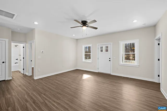 a view of empty room with wooden floor and fan