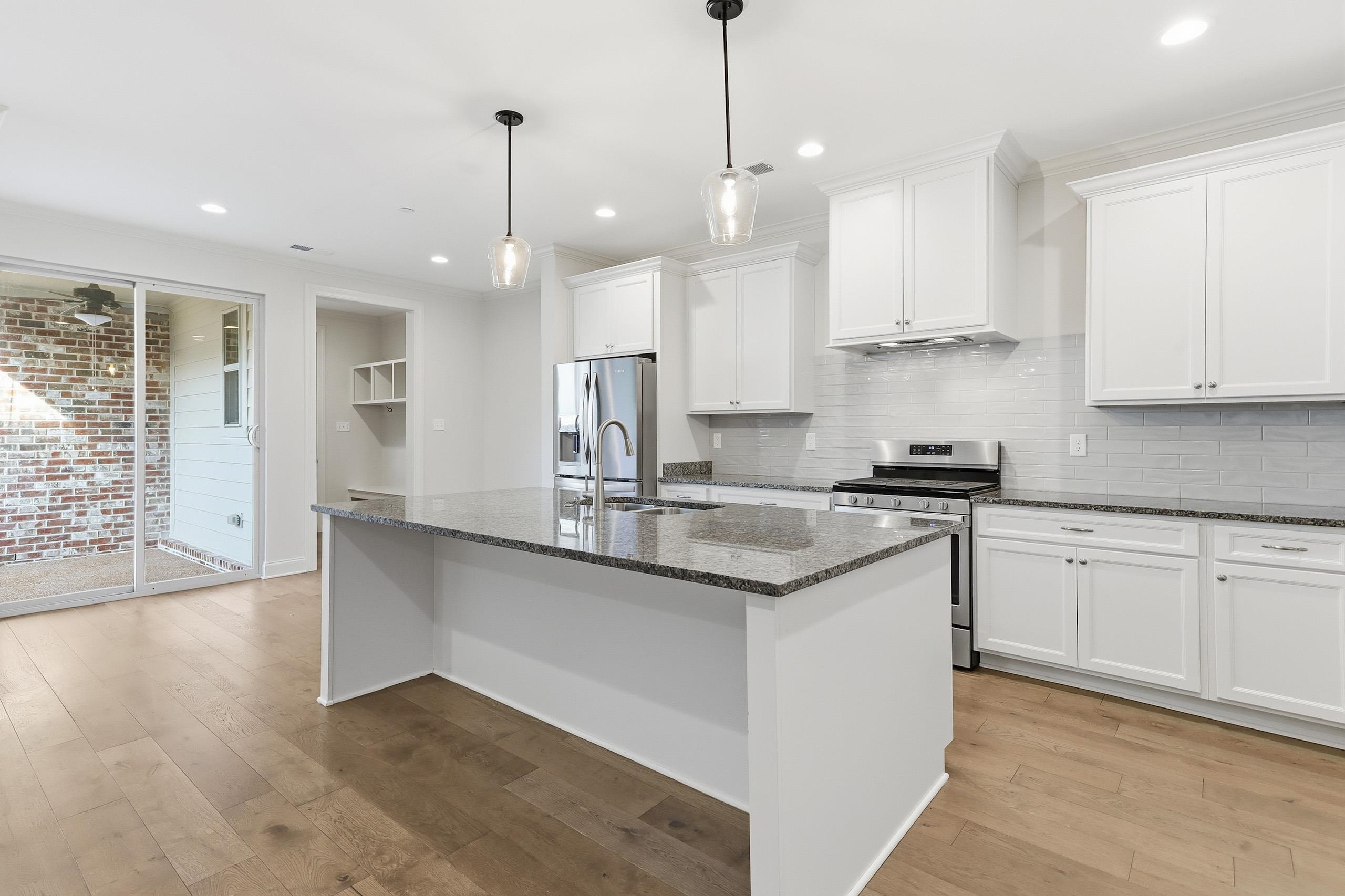 897 Ufton Alley Collierville, TN 38017 - Photo 1 of 32 a kitchen with stainless steel appliances granite countertop a sink a stove a refrigerator and white cabinets with wooden floor
