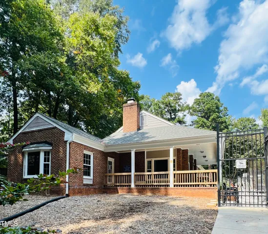 a front view of a house with a yard and a tree