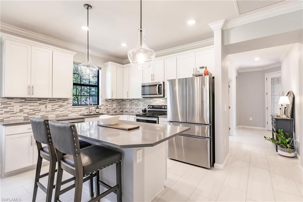 16637 Rolling Rock Boulevard Alva, FL 33920 - Photo 16 of 46 a kitchen with stainless steel appliances granite countertop a refrigerator a sink a stove a dining table and chairs