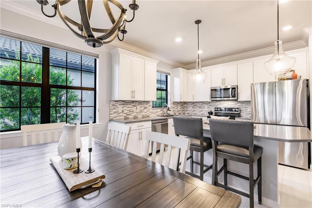 16637 Rolling Rock Boulevard Alva, FL 33920 - Photo 20 of 46 a kitchen with stainless steel appliances kitchen island granite countertop a refrigerator a stove a microwave oven a dining table and chairs with wooden floor
