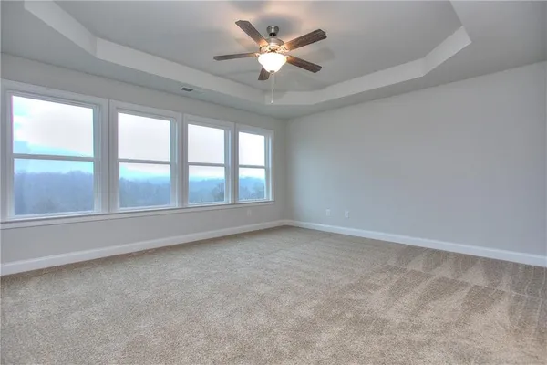 an empty room with chandelier fan and windows