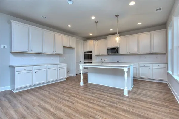 a kitchen with stainless steel appliances granite countertop a stove a sink and white cabinets