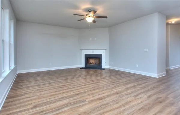 a view of room with wooden floor and a ceiling fan