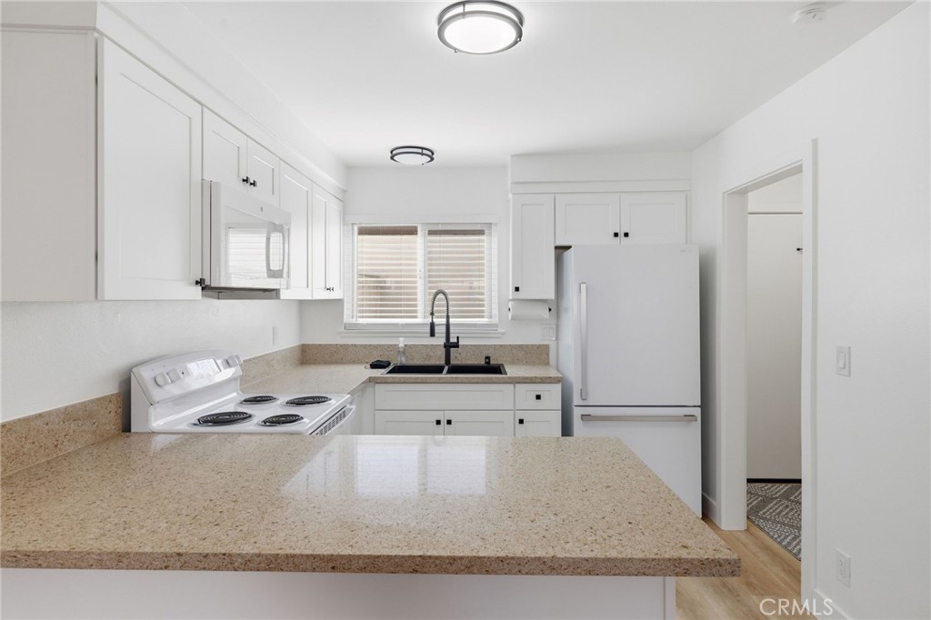 1722 Mitchell, Unit 152 Tustin, CA 92780 - Photo 8 of 25 a kitchen with granite countertop a sink stove and refrigerator