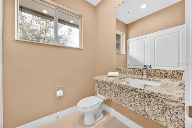 a bathroom with a granite countertop sink a toilet and a large mirror