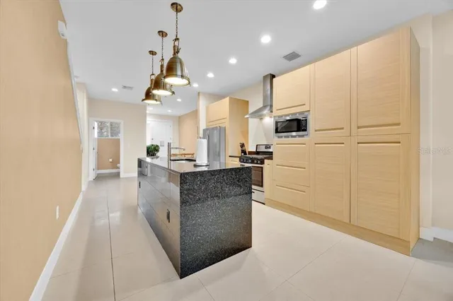 a large kitchen with kitchen island granite countertop a stove a sink dishwasher and a refrigerator with wooden floor