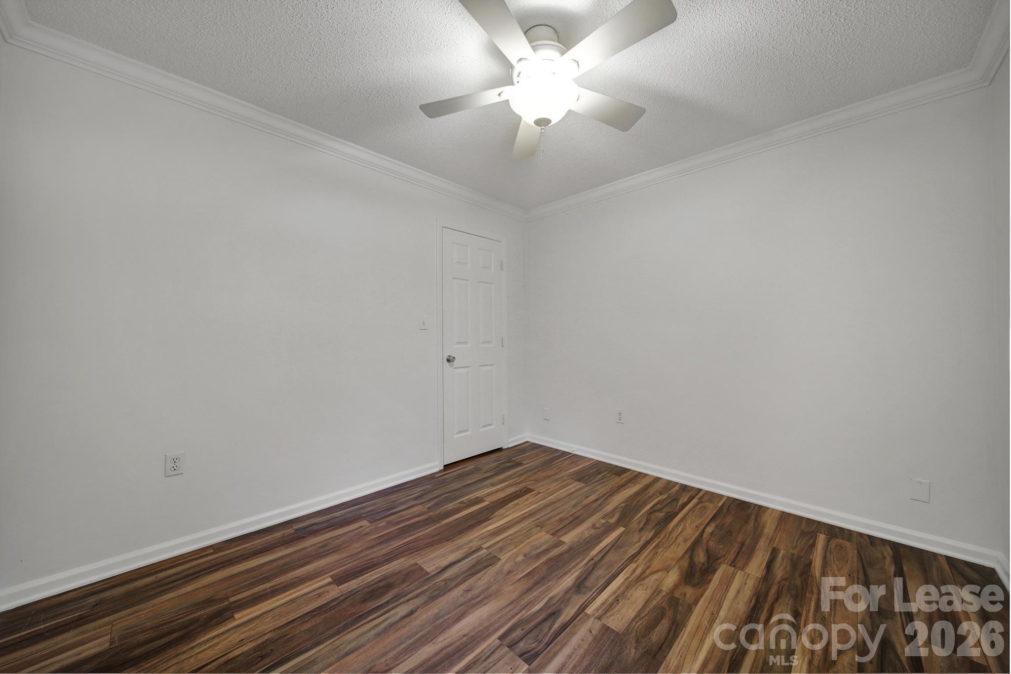 5007 Sharon Road, Unit E Charlotte, NC 28210 - Photo 13 of 24 an empty room with a chandelier fan and wooden floor
