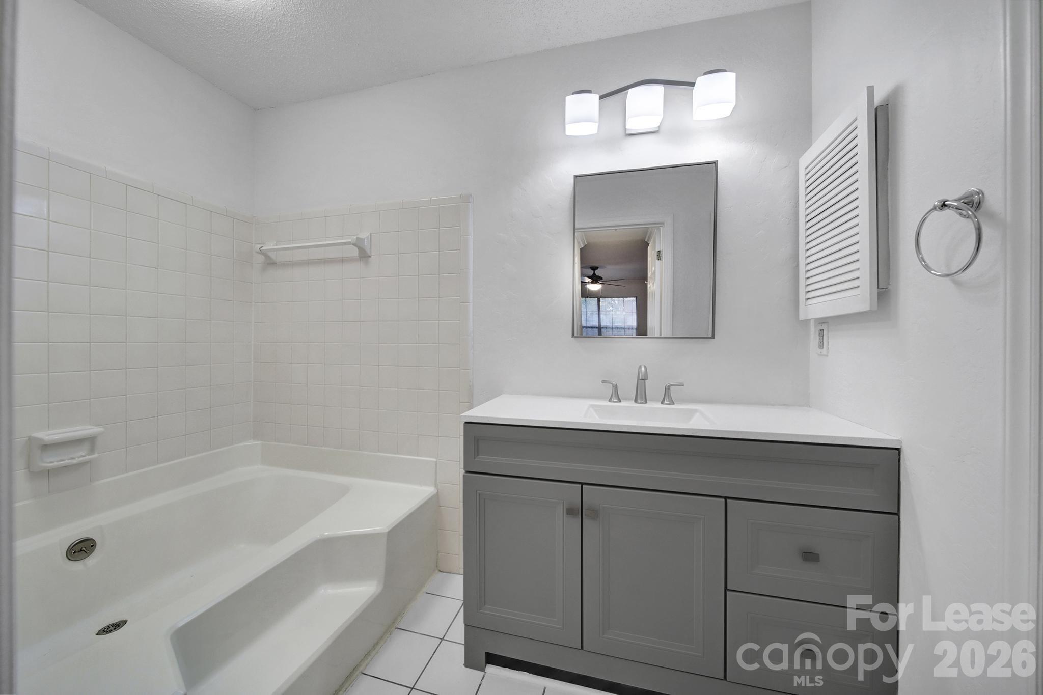 5007 Sharon Road, Unit E Charlotte, NC 28210 - Photo 18 of 24 a bathroom with a tub a sink and mirror