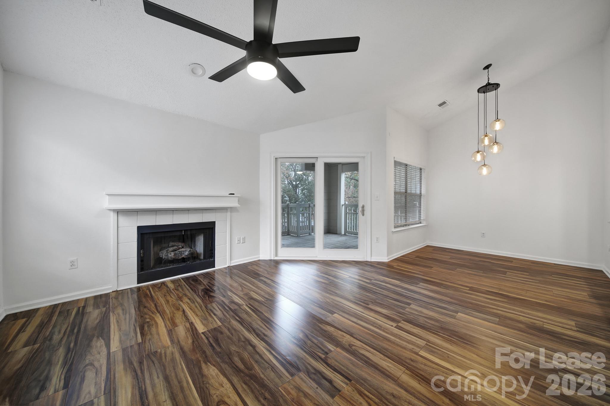 5007 Sharon Road, Unit E Charlotte, NC 28210 - Photo 4 of 24 an empty room with wooden floor fan and windows