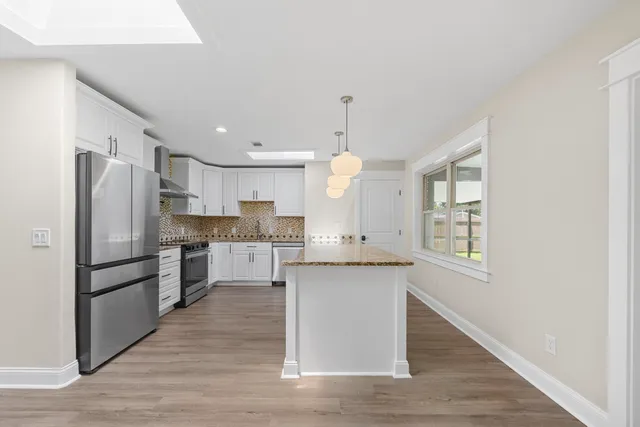 a kitchen with stainless steel appliances granite countertop a sink a stove refrigerator and cabinets