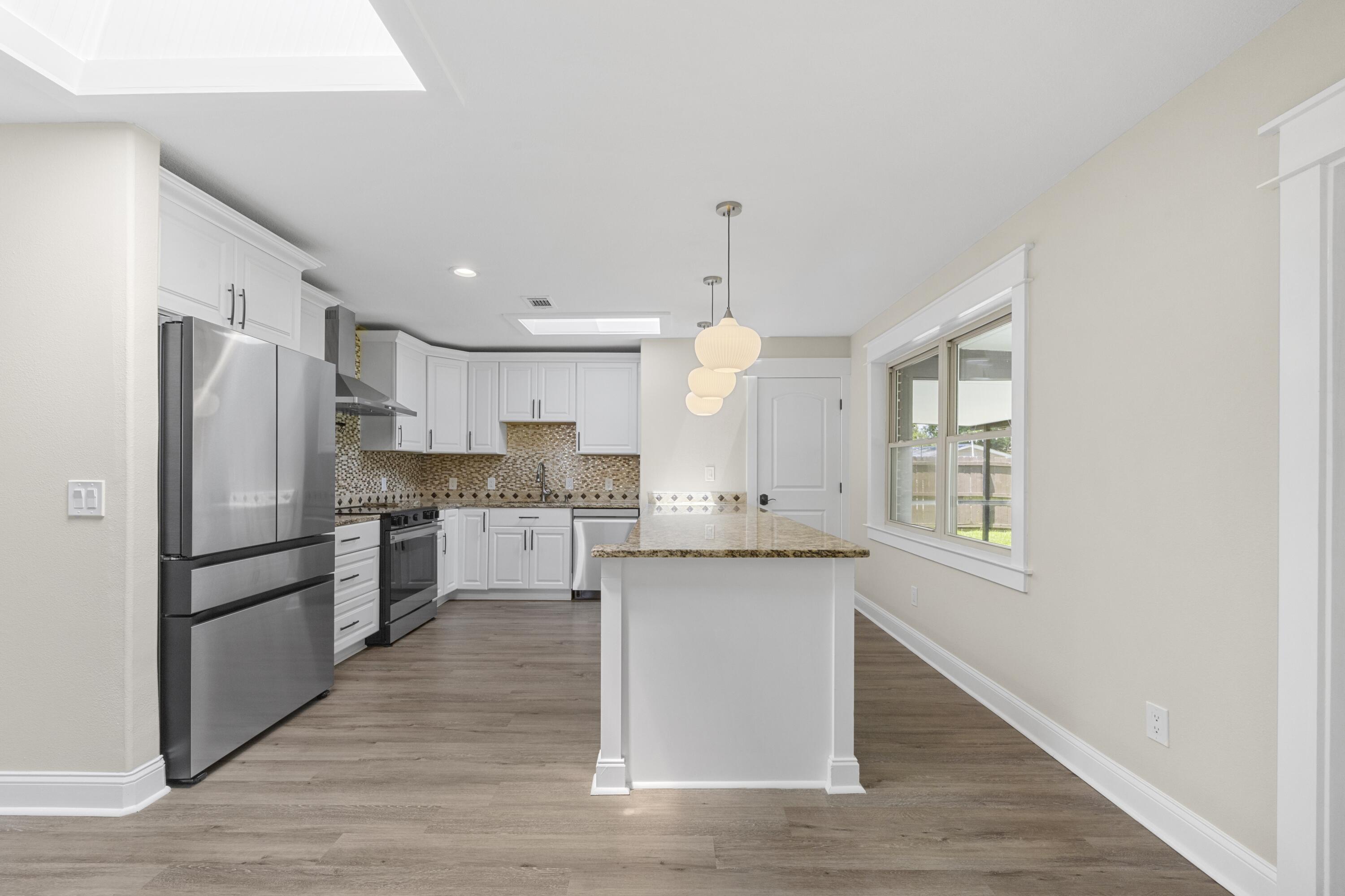 308 Spring Lane Destin, FL 32541 - Photo 8 of 47 a kitchen with white cabinets and stainless steel appliances