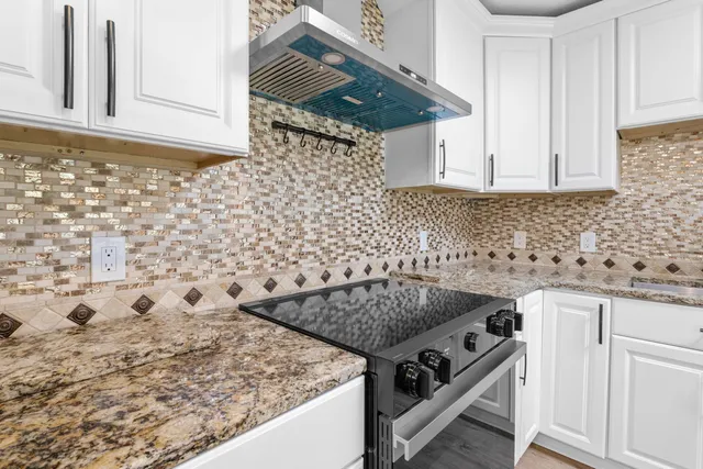 a large kitchen with stainless steel appliances granite countertop a oven a stove and a wooden floors