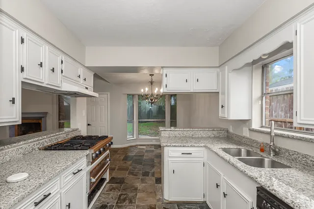 a kitchen with granite countertop white cabinets and refrigerator