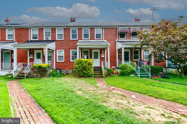 a front view of a house with a yard and potted plants