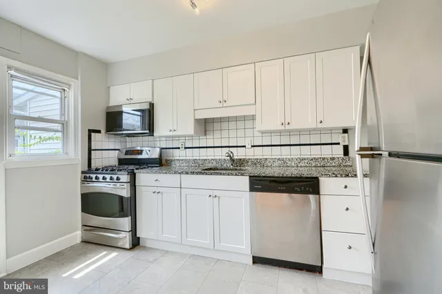 a kitchen with granite countertop white cabinets and stainless steel appliances