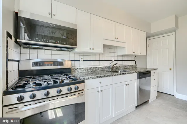 a kitchen with stainless steel appliances granite countertop a sink and a stove