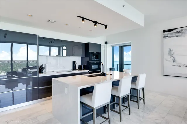 a kitchen with stainless steel appliances kitchen island granite countertop a table chairs in it and wooden floors