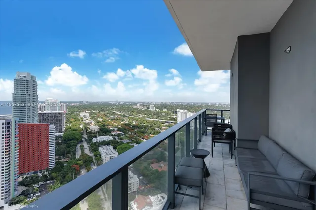 a view of a city from a balcony with dining table and chairs