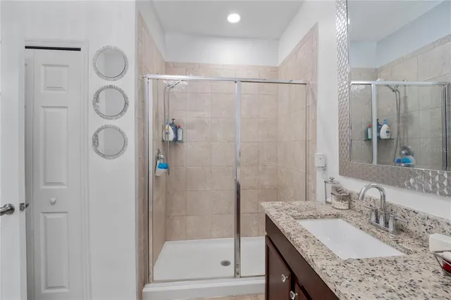 a bathroom with a granite countertop sink a mirror and shower