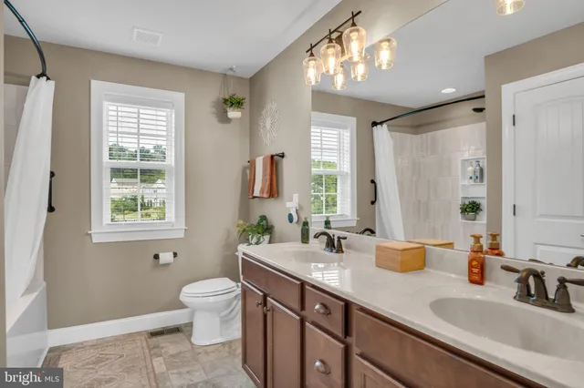 a bathroom with double vanity sink a mirror and a toilet