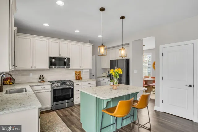 a kitchen with stainless steel appliances granite countertop a sink a stove a refrigerator cabinets and chairs