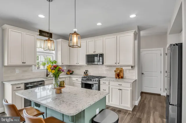 a kitchen with granite countertop a stove a sink a center island and cabinets