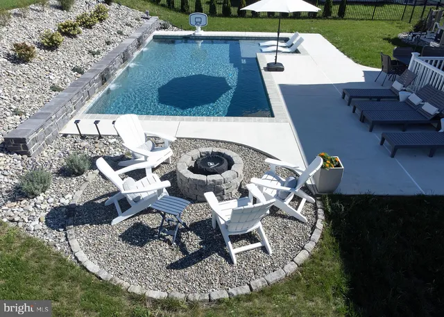 a view of a pool with a dining table and chairs under an umbrella