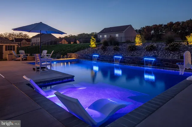 a view of a swimming pool with lawn chairs under an umbrella