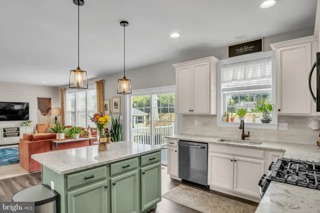 a kitchen with stainless steel appliances a sink a stove a refrigerator a center island and a wooden floor