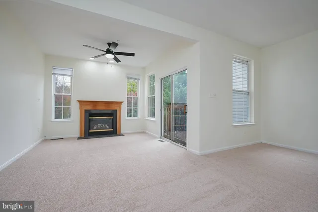 an empty room with windows fireplace and fan