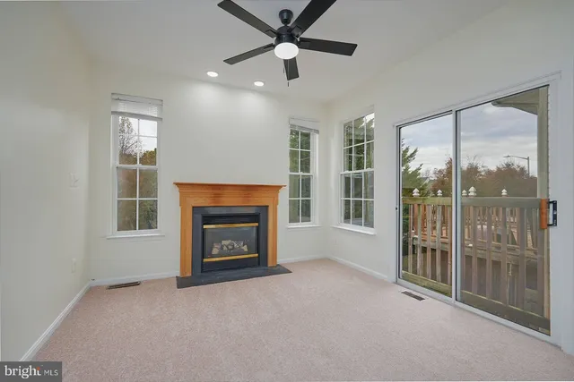 an empty room with fireplace fan and windows